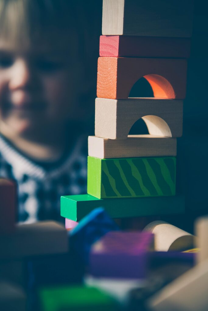 A child plays with colorful wooden blocks, building creative structures.