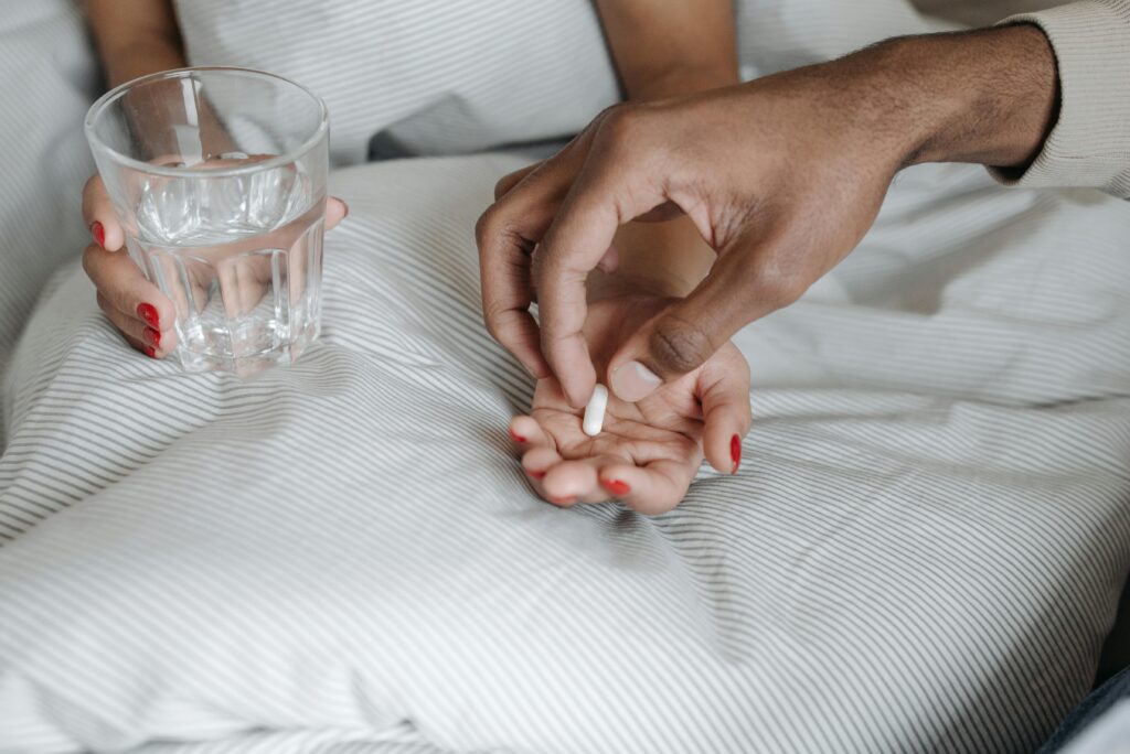 Close-up of hands offering a pill with a glass of water, symbolizing care and medication.